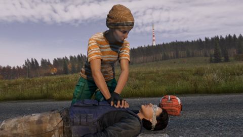 A survivor kneels to treat a wounded player in a field.